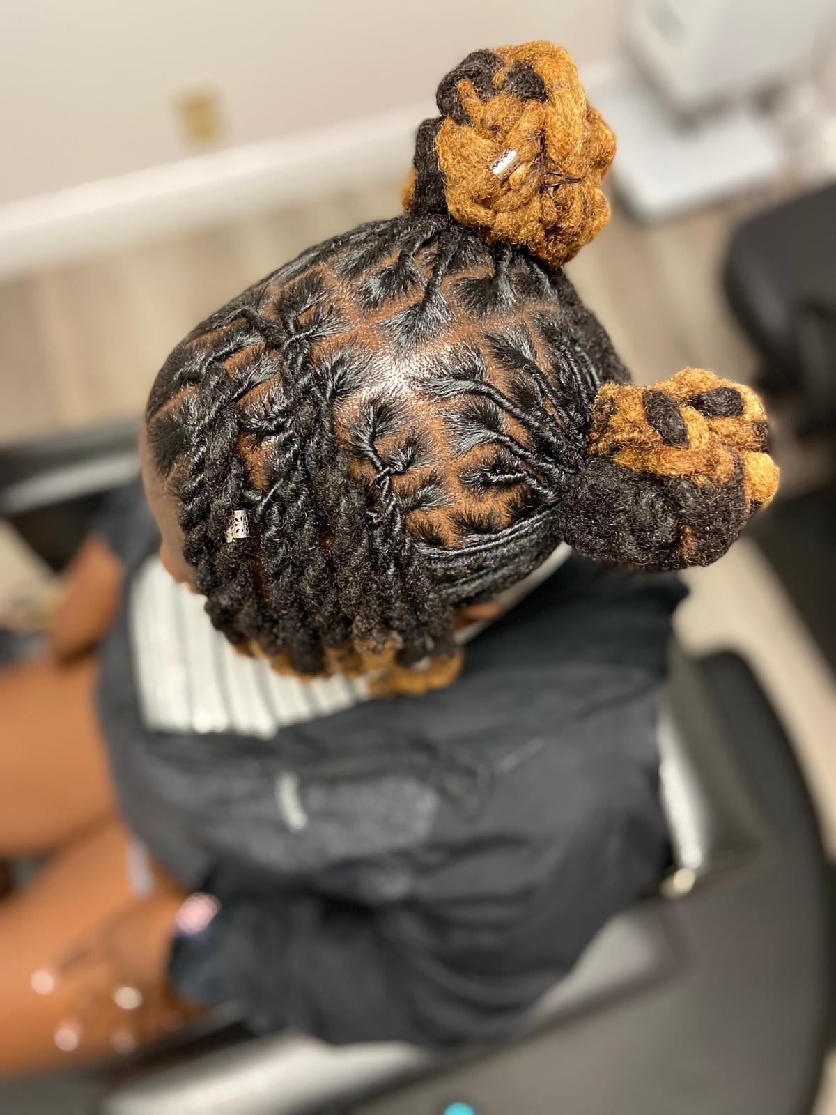 Intricate crown locs styled in an elaborate updo pattern with golden highlights, showcasing expert craftsmanship and artistic crown loc styling