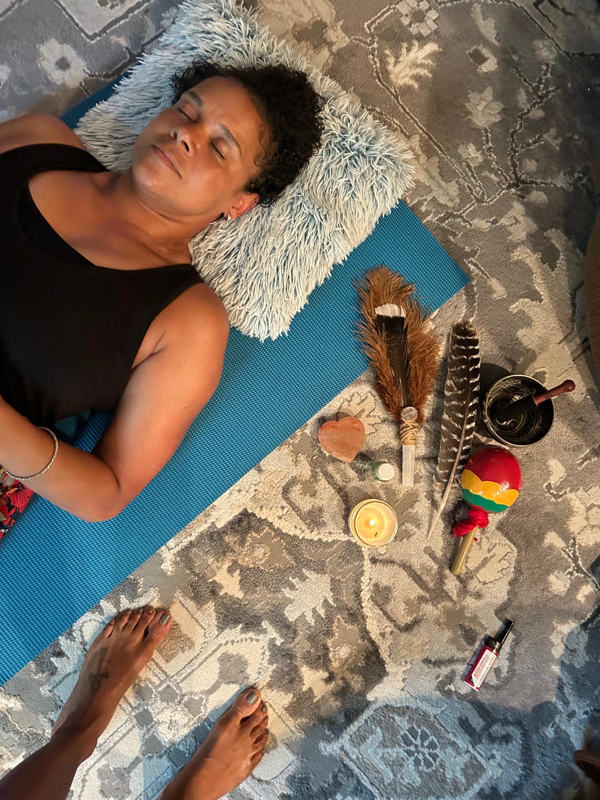 Client in deep meditative state surrounded by healing crystals, feathers, and sacred tools during energy healing